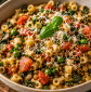 A rustic bowl of cucuzza leaf pasta with tomatoes, lentils, sweet peas, garlic, basil, and grated Parmesan cheese in a rich homemade tomato sauce.